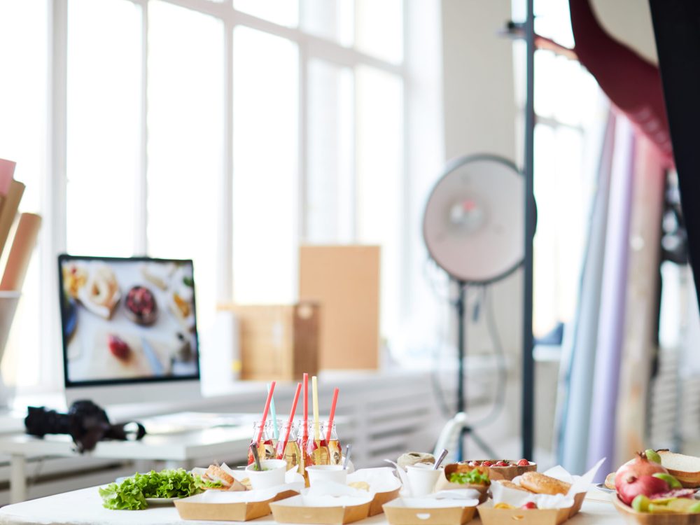 Background image of photo studio with party table with fast food in foreground, copy space